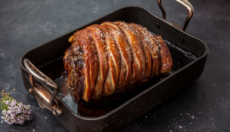Cooked pork loin in a baking tray with sea salt and crackling